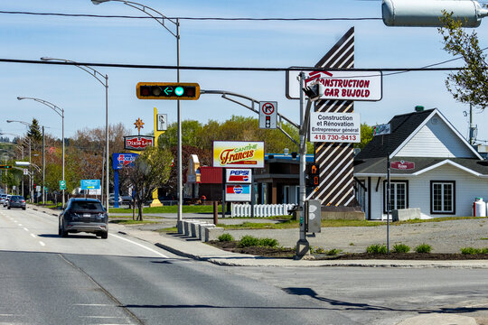Gaspesie, Canada, 30 May 2026 : Cars drive past a street intersection with commercial signs for Dixie Lee, Cantine Francis, and Construction Gar Bujold.