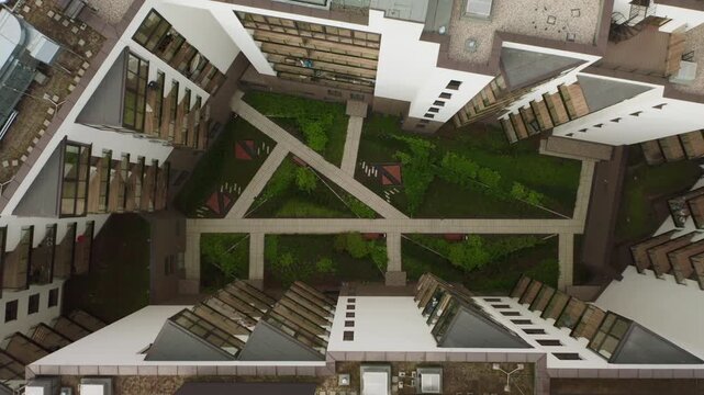 Modern apartment building inner courtyard with green garden and walking paths. Ascending motion reveals the residential complex flat roof, ventilation systems and urban real estate.