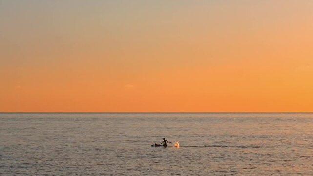 Man paddling on stand up paddleboard in the sea at sunset minimalist view.