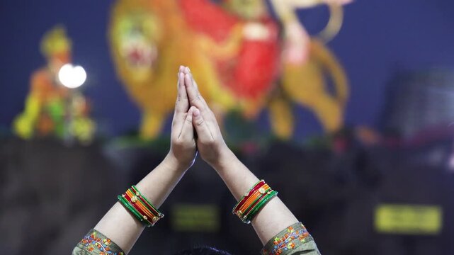 woman offering prayer with folded hands before goddess durga idol during navratri festival