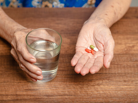 Senior woman holding medication and glass of water
