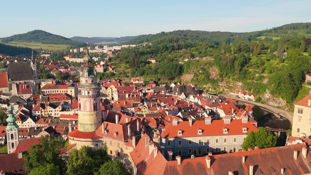 Cinematic aerial view of Cesky Krumlov historic town center at sunrise. Drone shot of beautiful medieval architecture, Vltava river, castle tower, and red roofs. Czechia, UNESCO World Heritage Site