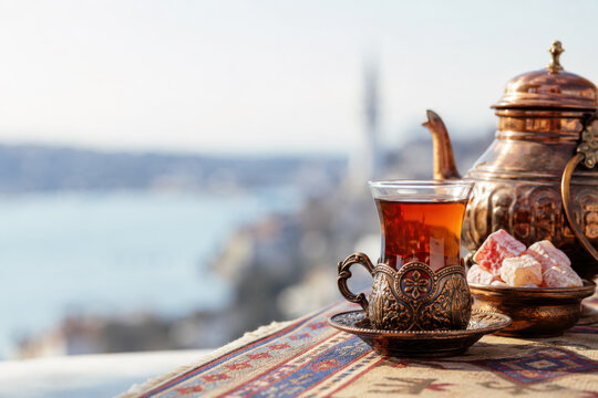 Turkish tea in armudu glass with turkish delight sweets against blurred Istanbul Bosphorus background.