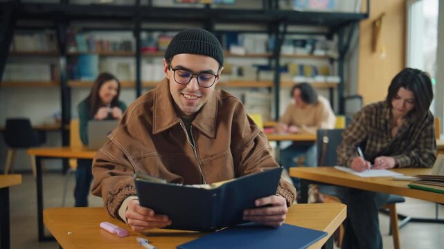 College students study in library with books and laptops during afternoon session, focusing on coursework and group projects