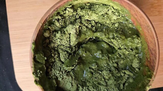 "Thick organic Ziziphus spina-christi (Sidr) herbal paste being stirred, natural hair mask preparation, top view."