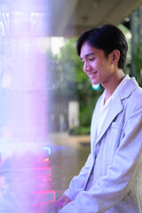 Obraz premium Smiling young nonbinary Thai business professional playing arcade claw machine game