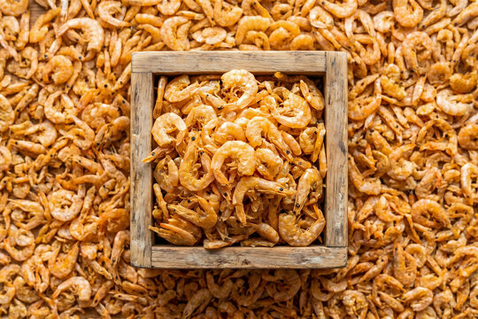 Dried small shrimps in wooden box top down food texture background