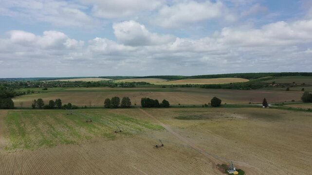 Aerial top view of a green agricultural tractor spraying chemicals, fertilizer, or pesticides on a large farming field with visible rows.