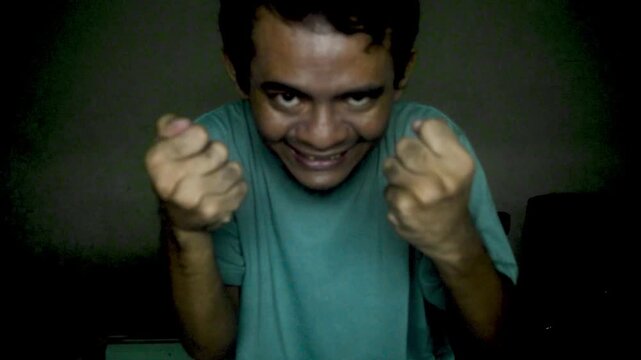 Sinister Man With Evil Expression Reaching Towards Camera In Dimly Lit Room