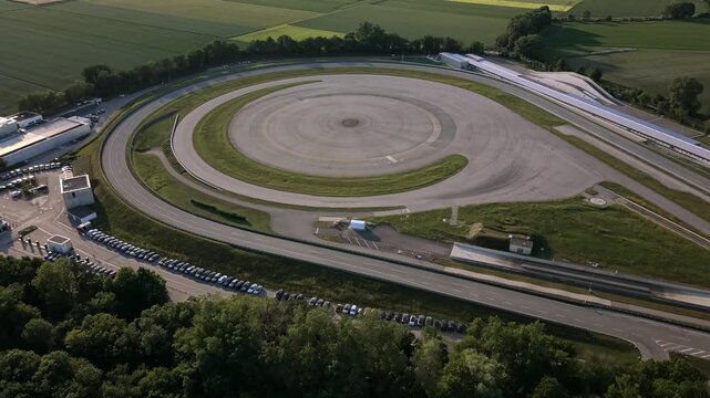 Cinematic aerial video of an automotive testing center in Germany with structured proving tracks, performance lanes and surrounding rural farmland