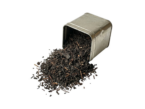 Isolated dry black tea leaves spilled from an open silver metallic tin canister