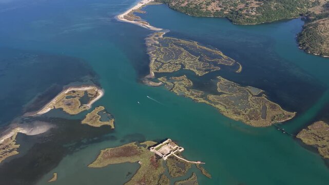 Aerial view of Ali Pasha Castle situated on a small island surrounded by turquoise waters and lush coastal wetlands in Mahala, Qarku i Vlores, Albania.
