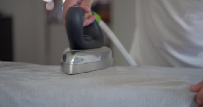 Ironing Clothes on Board: A person is ironing clothes on an ironing board, a domestic chore highlighting everyday life and household tasks.