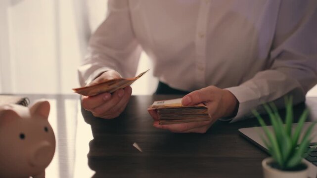 Businesswoman's hands meticulously counting stack of fifty euro banknotes at modern office desk, concepts of savings, financial success, profit, and economic stability