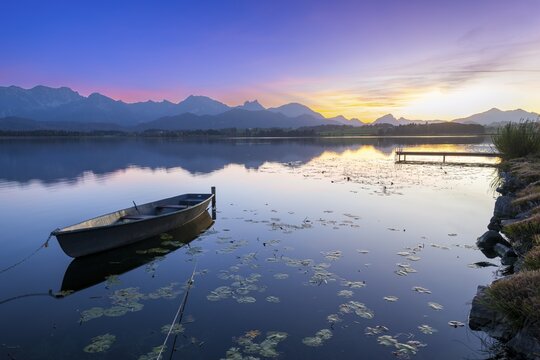 Boats at a jetty on a calm lake at sunset with mountains in the background, Hopfensee, Hopfen am See, Ostallg&auml;u, Allg&auml;u, Swabia, Bavaria, Germany