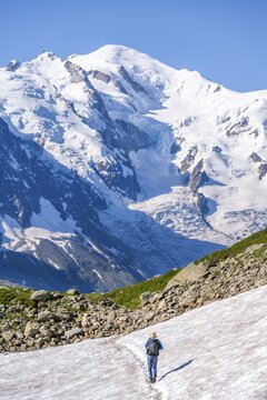 Mountaineer crossing a snowfield, view of spectacular glaciated peaks of Mont Blanc, Mont Blanc massif, Aiguilles Rouges, Chamonix-Mont-Blanc, Haute-Savoie, France