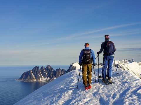 Two ski mountaineers at the summit of Husafjellet with a view over Devils Teeth, Okshornan, Senja Island, Troms, Norway