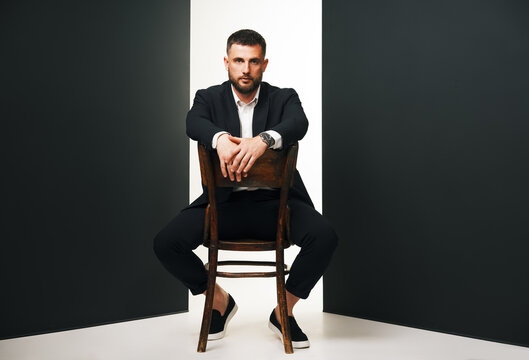 Handsome man in black suit on wooden chair
