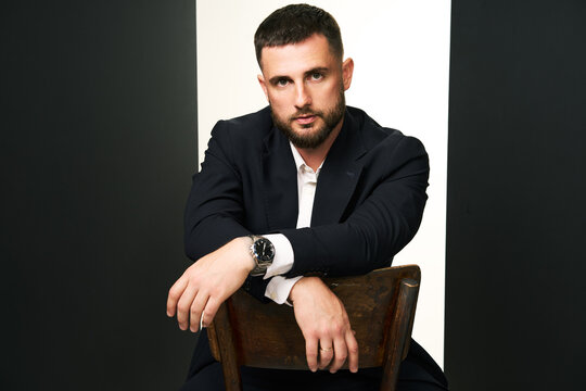 Handsome man in black suit on wooden chair