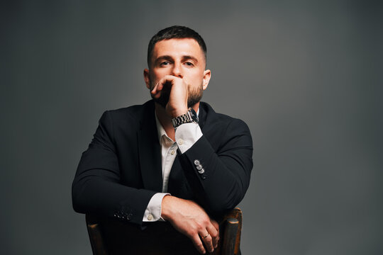Handsome confident man in black suit on chair
