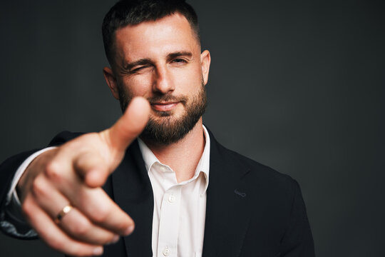 Confident handsome businessman winking and pointing finger