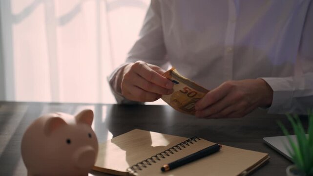 Businesswoman holding a stack of euro banknotes and gesturing with confidence at her office desk. Salary payment, income, financial reward and successful career concept.