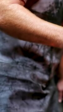 Vertical video: Moving arm starting man grabbing hammer and tongs at forge forging metal soot apron