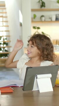 Vertical video: Reacting to high-five, child in white top using tablet, notes at home mom guiding