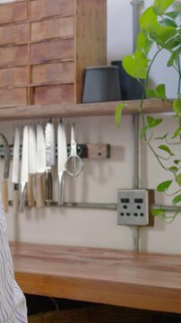 Vertical video: Leaning senior in striped tee placing cup on counter at home making tea, copy space