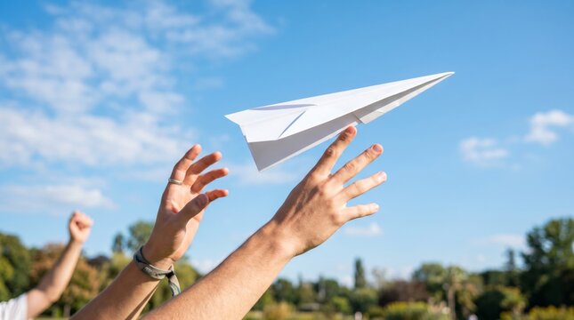 A young man launches a paper airplane into the clear blue sky, symbolizing creativity and freedom.