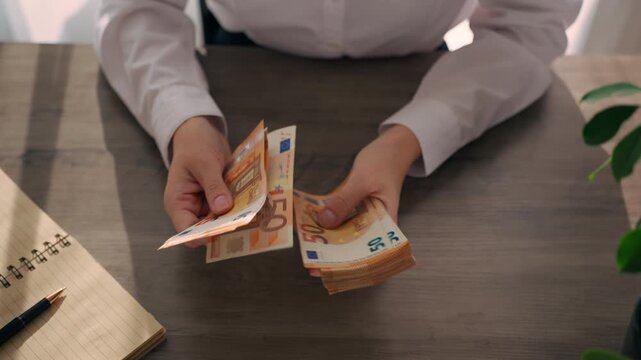 Businesswoman counting euro banknotes at desk,symbolizing wealth distribution,financial inequality,economic differences in European business environment.Wealth gap,financial inequality,Europe economy