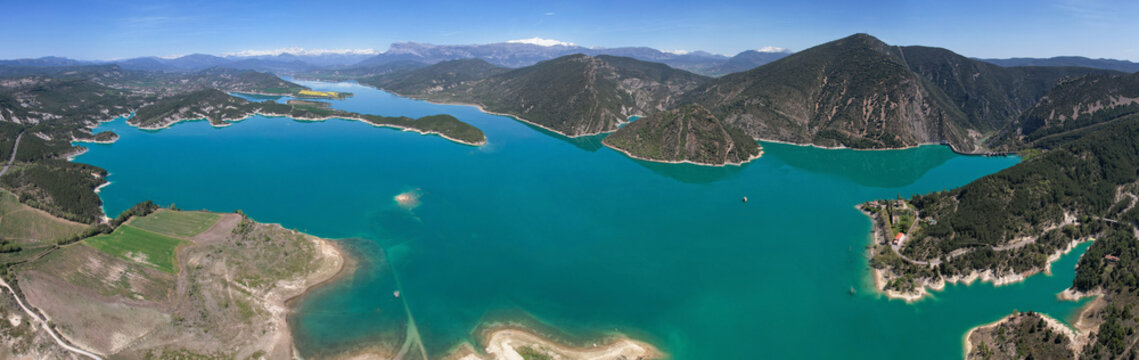 Panoramic aerial view of Mediano Reservoir and covered with snow Pyrenees on the background on sunny spring day. Huesca, Spain.