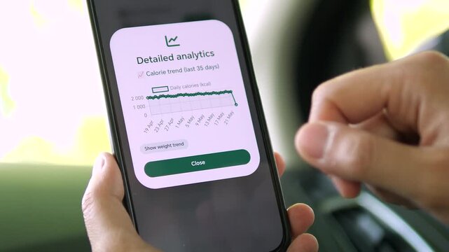 Detailed analytics screen with a line graph showing daily kcal consumption. Hand holding phone with clean interface design. Great for app developers, medical monitoring, and lifestyle data reports.