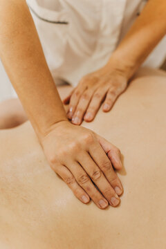 Close up of back massage therapy session. Female massage therapist's hands.