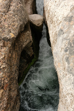 A stone stuck in a crevice above the river Algars. Charca del Molino (natural limestone pool),. Arnes, Spain.