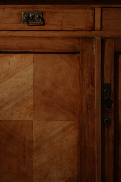 Detail shot of an old retro wooden sideboard or wardrobe under dramatic warm lighting with hard shadows. Concept of restoration, antiquity, and home interior