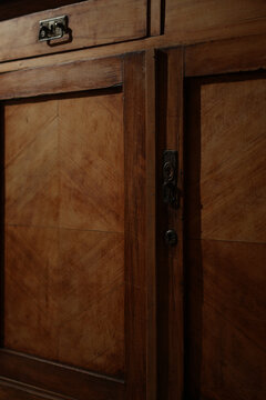 Detail shot of an old retro wooden sideboard or wardrobe under dramatic warm lighting with hard shadows. Concept of restoration, antiquity, and home interior