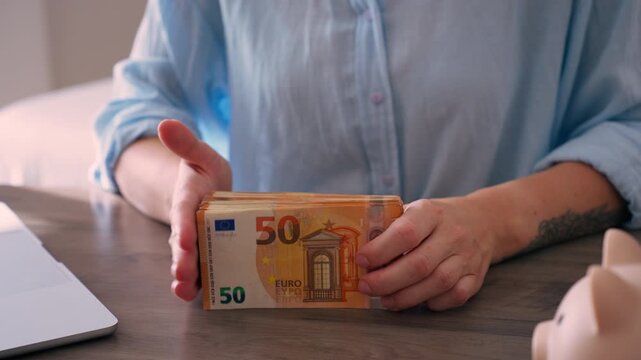 Woman documenting expenses after counting euro banknotes at desk. Personal budgeting, expense tracking, financial planning, money management concept. Managing household finances and recording spending