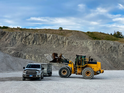 Wheel Loader Loading Gravel Into Utility Trailer at Rock Quarry