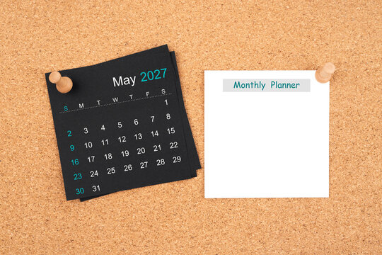 May 2027 Black calendar and blank adhesive notes for monthly planner with thumbtack on board.