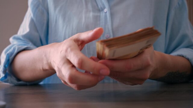 Close up view of woman hands counting thick stack of euro bills, representing concepts of salary, income, savings, and wealth management after successful transaction