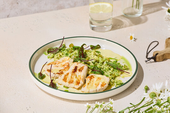 Turkey medallions with pesto couscous and greens on a sunny summer table with copy space for menu