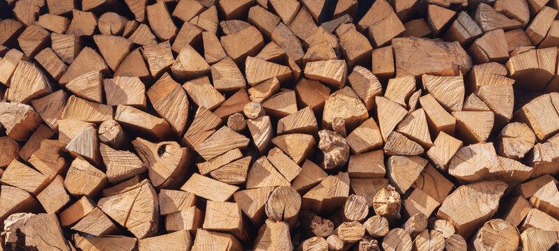 Firewood stack texture with cut wooden logs arranged as natural background for energy and heating