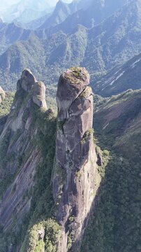 4K aerial drone footage of the iconic Dedo de Deus granite spire emerging from the Atlantic Forest canopy in Brazil.