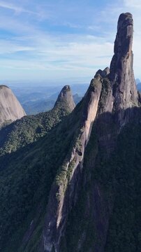 Drone footage descending toward the base of Dedo de Deus with the full granite formation visible.