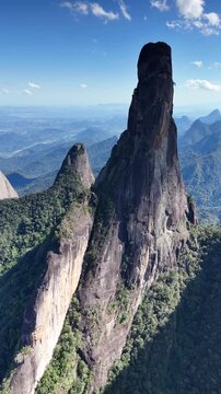 Overhead drone perspective of Dedo de Deus granite spire rising sharply above the dense jungle canopy.