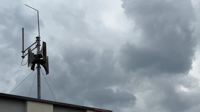 Alarm siren mounted on the roof of a building, installation of a siren emitting warning sounds to the public