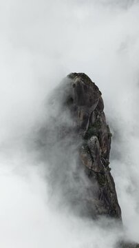 Slow aerial approach toward the Finger of God peak with soft natural light on the granite surface.
