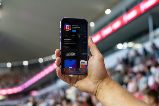 MINSK, BELARUS JUNE 9, 2026: Man holding a purple Apple iPhone 14 Pro in the stadium. The official FIFA mobile application selling tickets for the 2026 FIFA World Cup in the USA, Mexico, Canada.