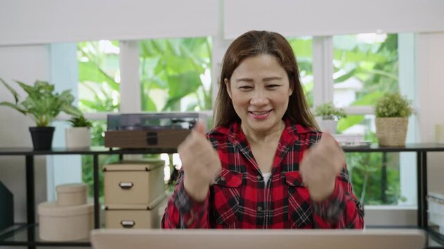 Yeah! Happy excited Asian businesswoman sitting using a laptop computer to check email and message, receiving good news about business work and a big seal deal closed with joy at desk in the office. 
